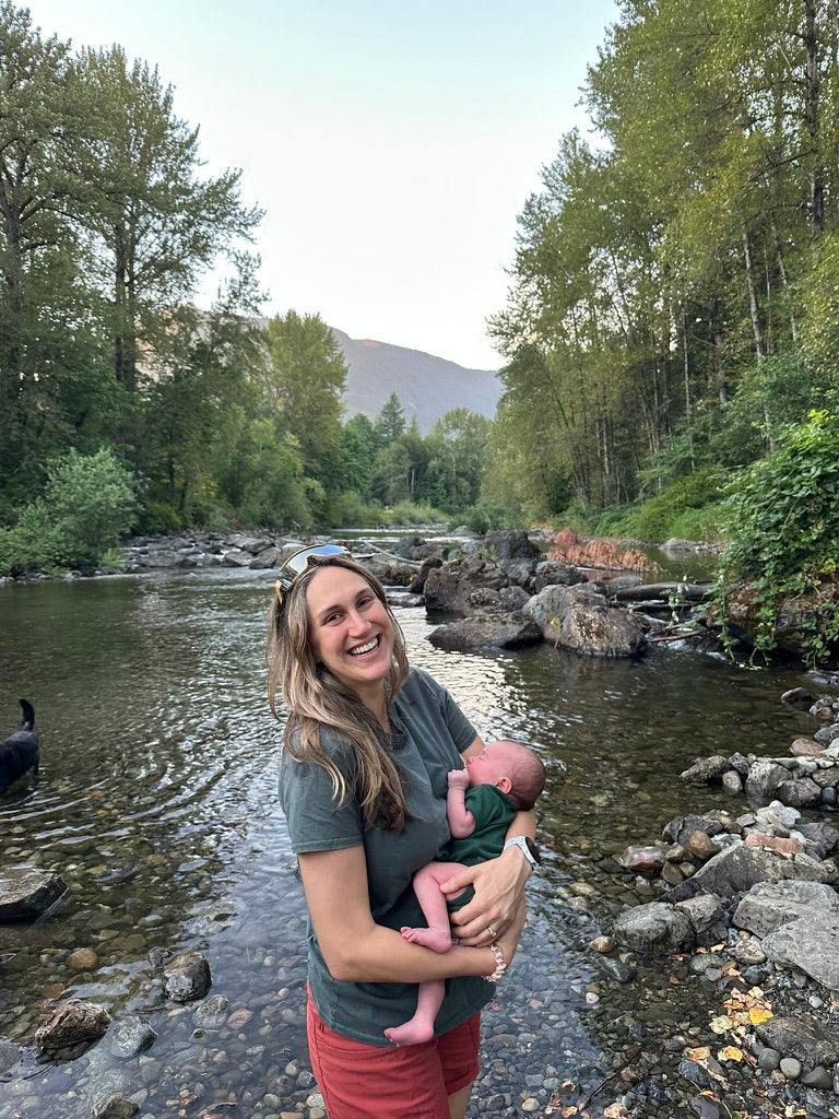 Mom holding baby by a mountain creek
