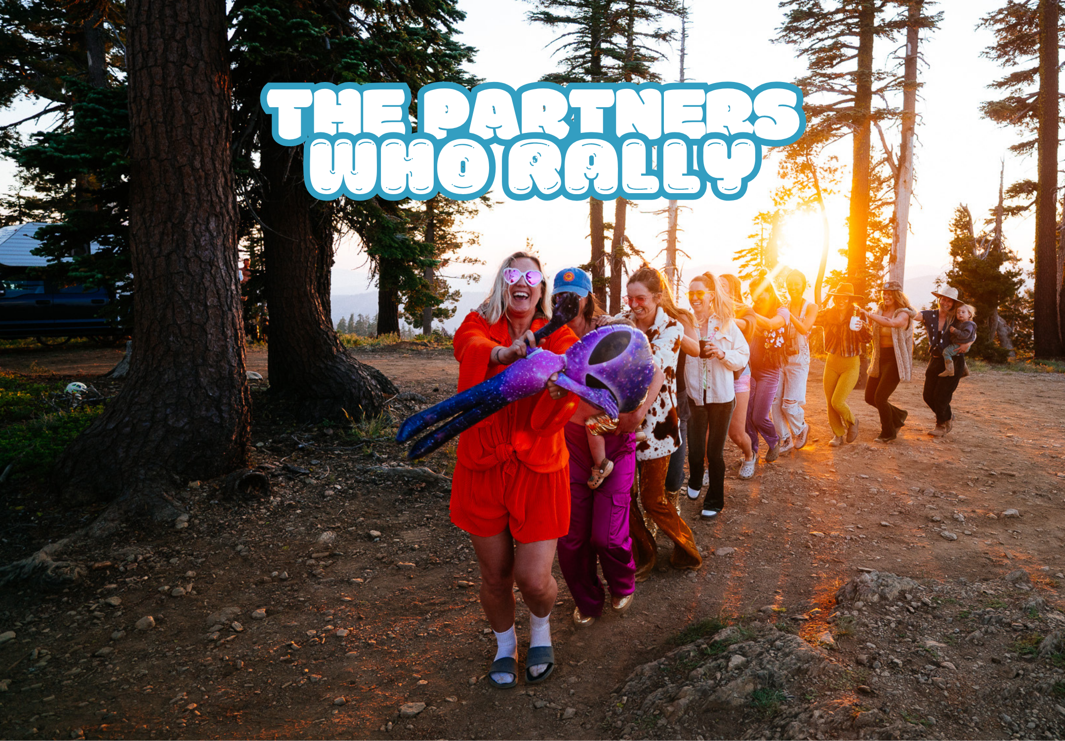A group of people running and laughing down a forest path at sunset, with the text 'THE PARTNERS WHO RALLY' overlaid at the top. The foreground person wears an orange outfit and holds a purple and blue toy.